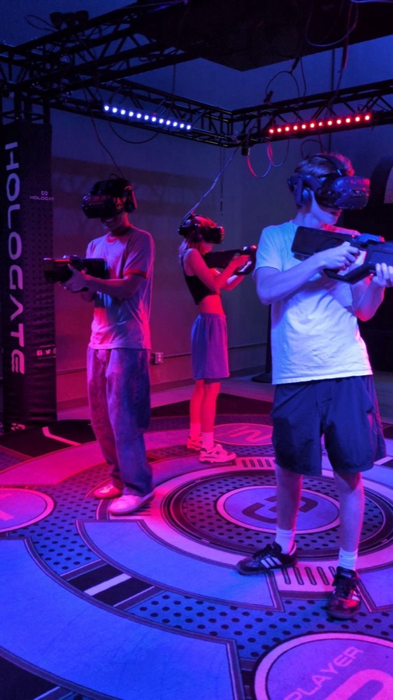 Three players in VR headsets in a neon-lit arena